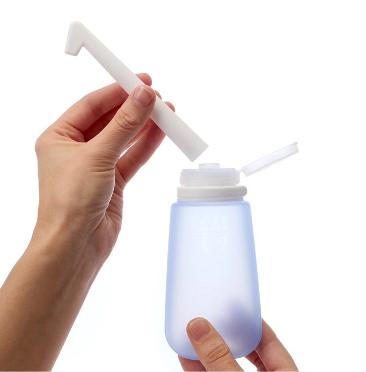 Hand placing BidetToob spout onto the base of the silicone bottle. 