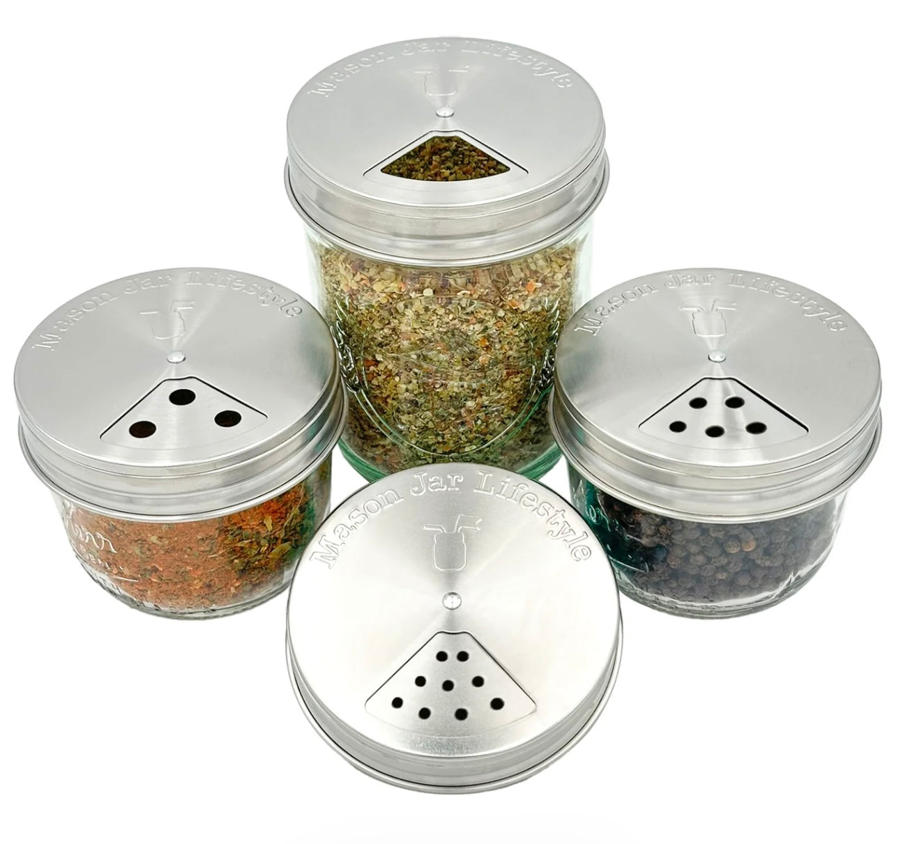 Set of four glass spice jars with metal lids on a white background