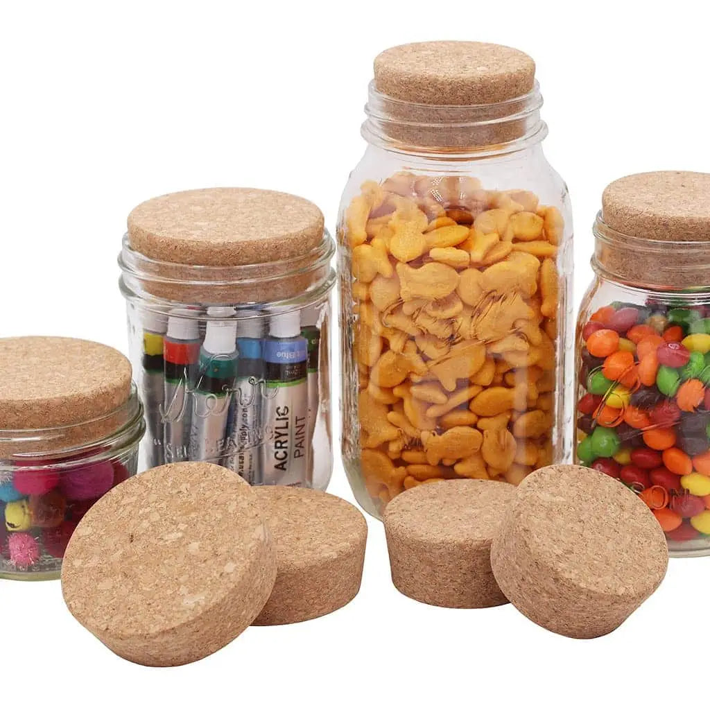 Glass jars with cork lids containing various items on a white background