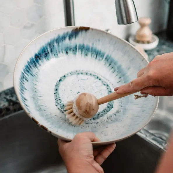 Person using brush on dish. 
