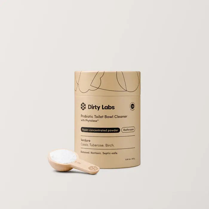 Container of Dirty Labs probiotic toilet bowl cleaner with a scoop of powder on a light background